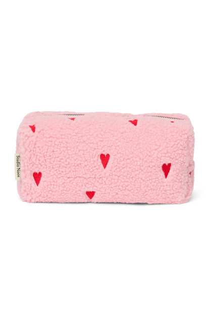 Vorderseite der Studio Noos Pouch aus pinkem Teddystoff mit gestickten roten Herzen und Reißverschluss