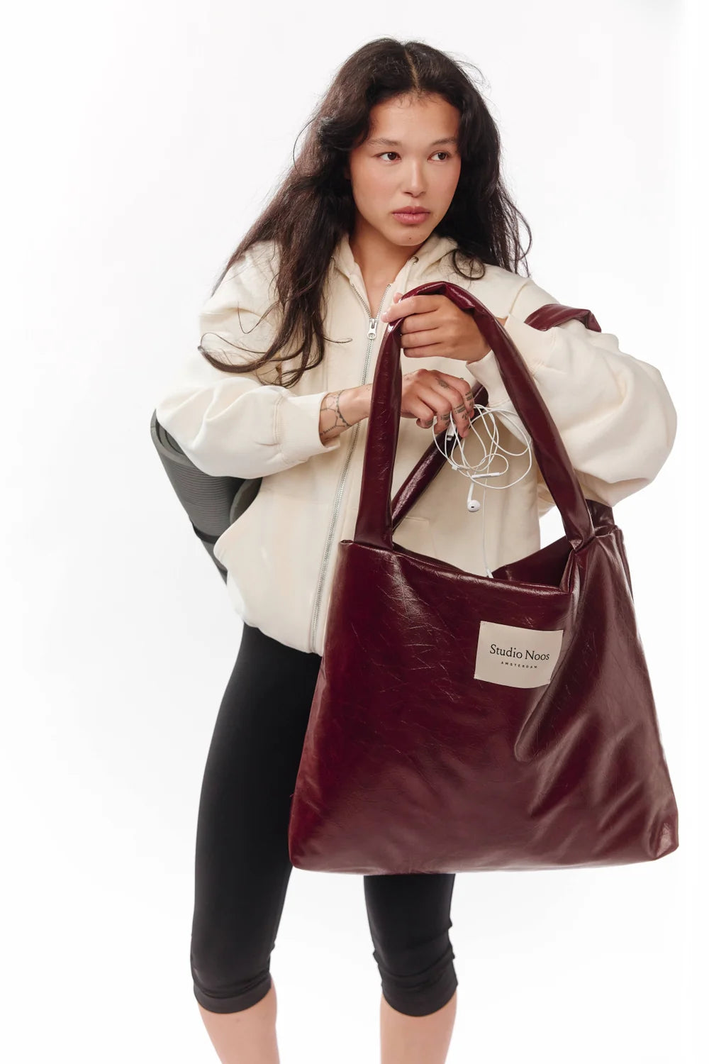 Foto: Frau Studio Noos Vegan Leather Mom Bag in Bordeauxrot mit gepolsterten Griffen und kleinem Studio Noos Amsterdam Label vorne