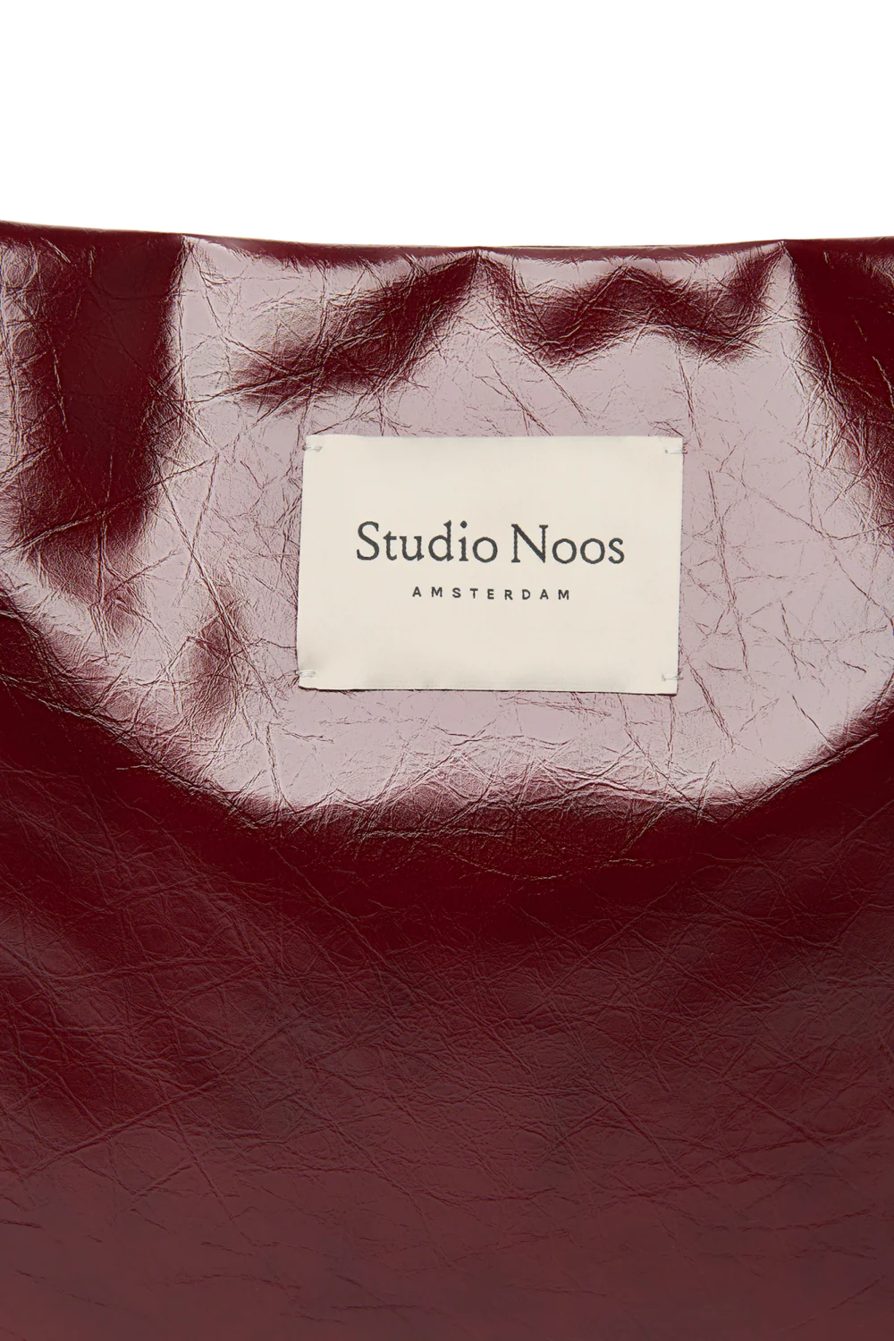 Detailansicht: Vorderansicht: Studio Noos Vegan Leather Mom Bag in Bordeauxrot mit gepolsterten Griffen und kleinem Studio Noos Amsterdam Label vorne