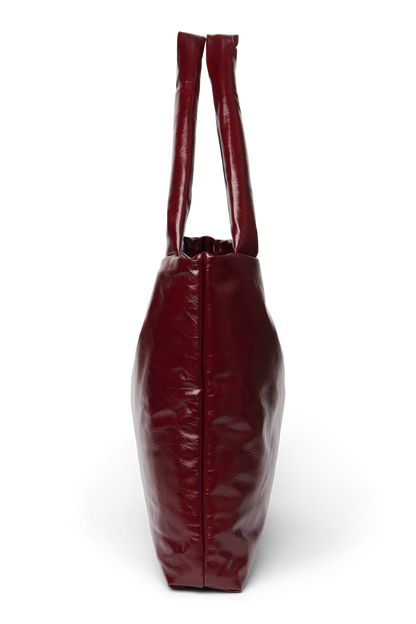 Seitenansicht: Studio Noos Vegan Leather Mom Bag in Bordeauxrot mit gepolsterten Griffen und kleinem Studio Noos Amsterdam Label vorne