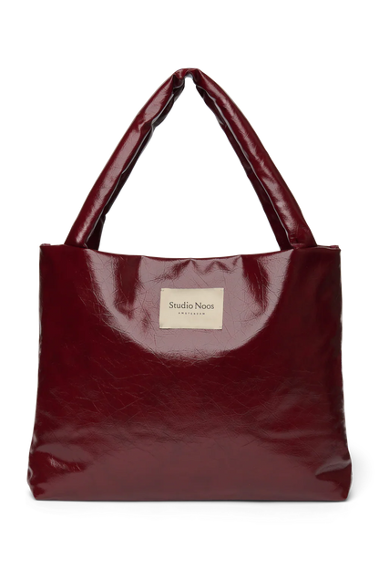 Vorderansicht: Studio Noos Vegan Leather Mom Bag in Bordeauxrot mit gepolsterten Griffen und kleinem Studio Noos Amsterdam Label vorne
