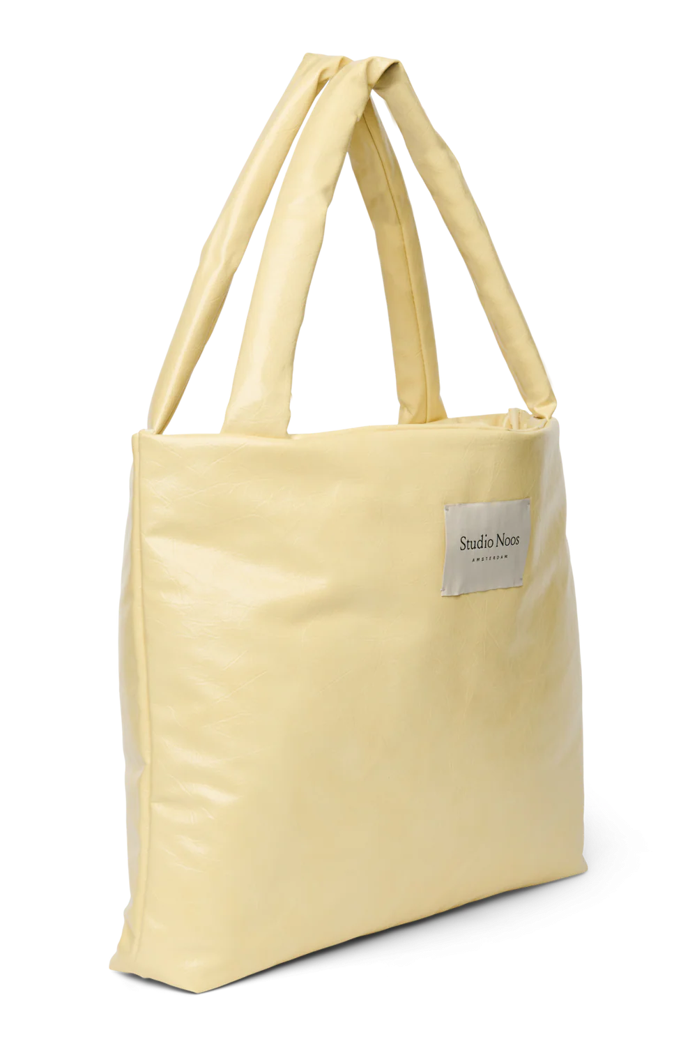 Seitenansicht: Studio Noos Vegan Leather Mom Bag in Buttergelb mit gepolsterten Griffen und kleinem Studio Noos Amsterdam Label vorne