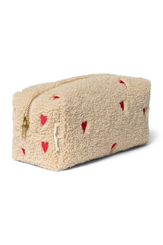 Mit Herzen bestickte Kulturtasche aus Teddystoff von Studio Noos. 