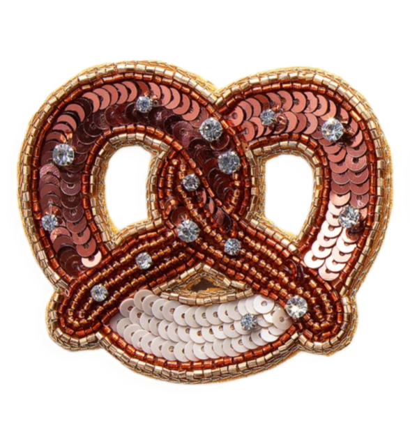 Brosche Brezel von byVivi in brauner Brezelform mit Pailletten, Perlen und funkelnden Steinen verziert.